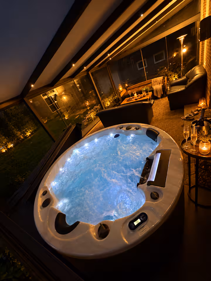 Private jacuzzi lit up inside the covered glass veranda in the evening